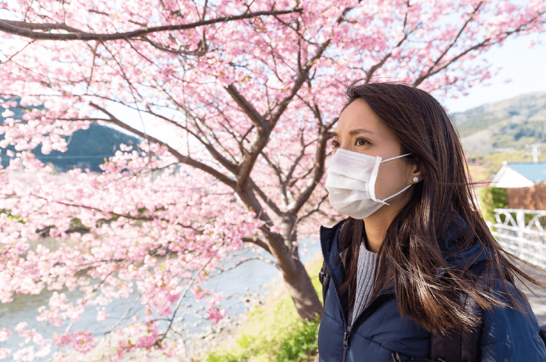 Woman wearing a face mask with a tree in the background