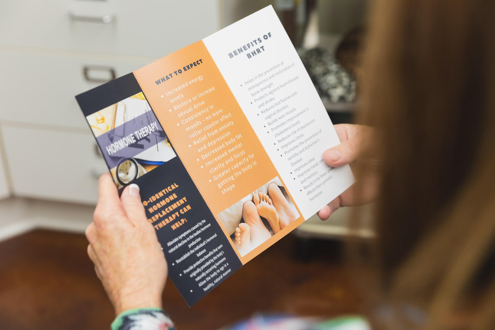 A patient reads a brochure about hormone replacement therapy near Belle Meade at Ona Skincare.