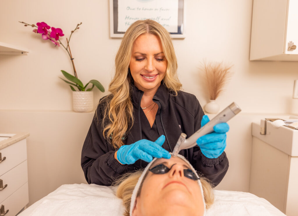 A woman performing microneedling on a female patient's forehead for skin toning in East Nashville.
